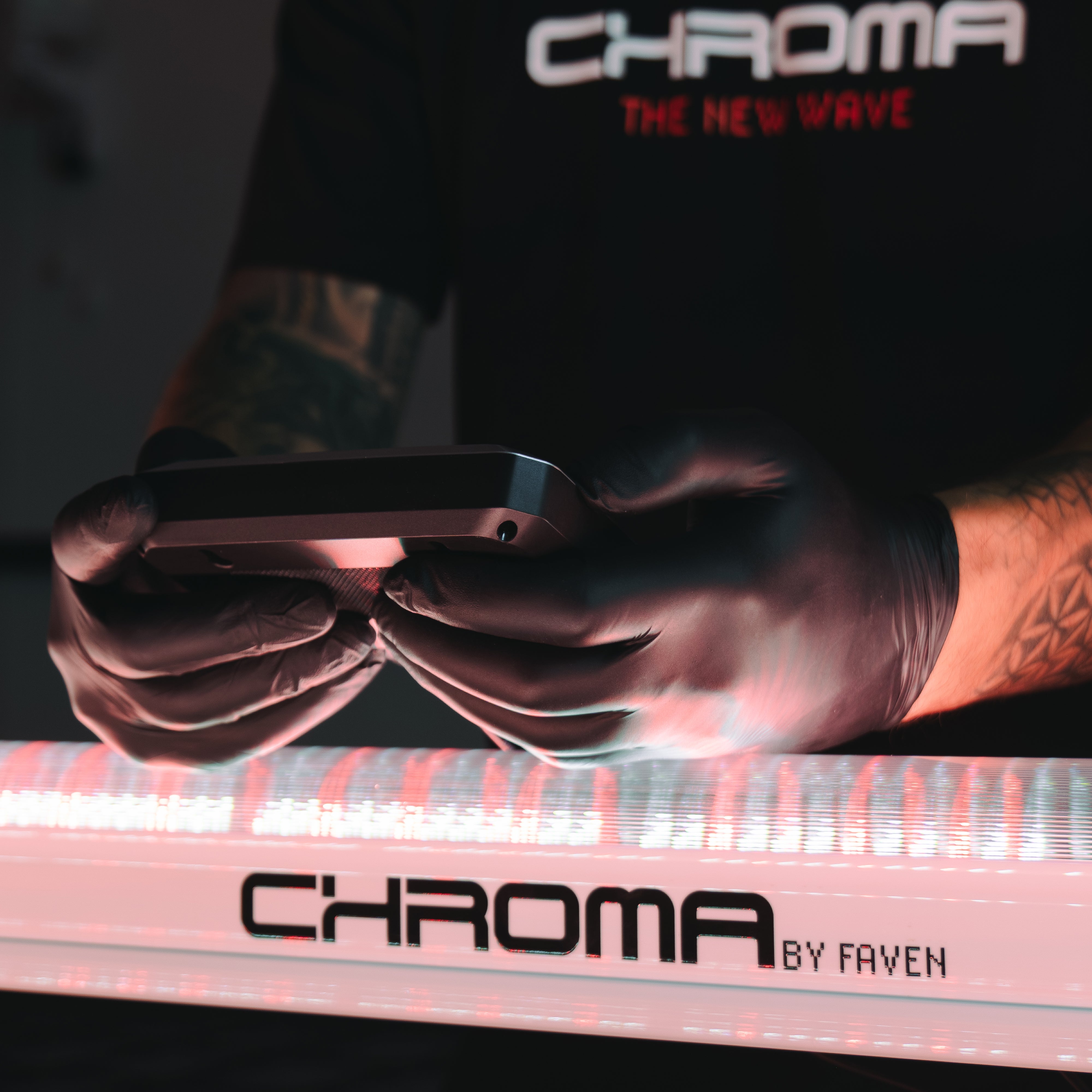 A close-up of a person's gloved hands operating an under canopy lighting controller next to a Faven LED light.