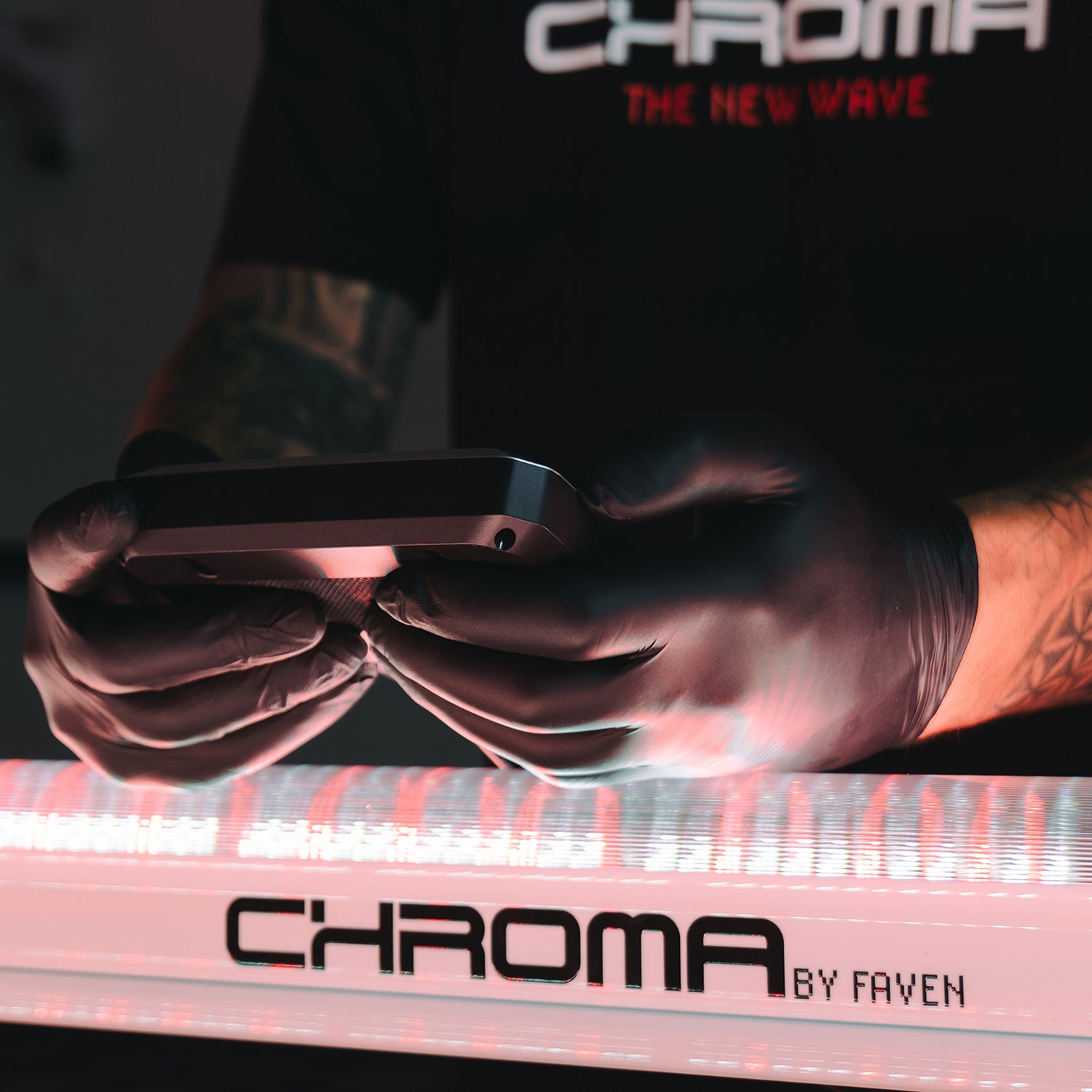 A person weaning rubber gloves holding a Faven MX2 Controller to adjust the under canopy light settings at an indoor grow.
